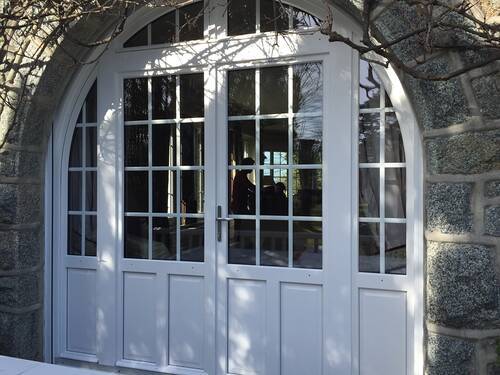 Magnifique porte fenêtre à double battant. Vitrage petit carreaux et imposte pour un aspect traditionnel. Cintrage bois et couleur blanche.